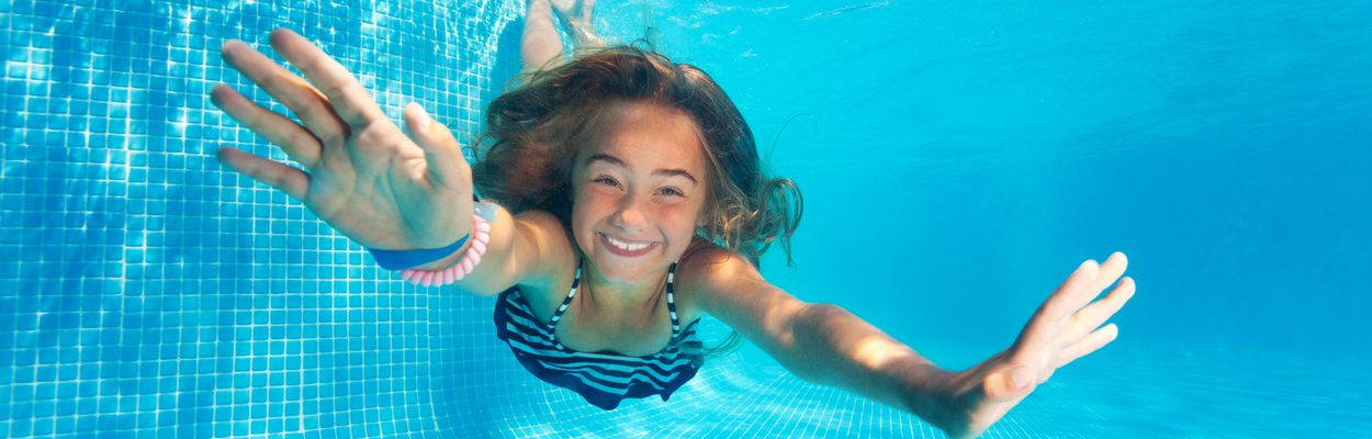Portrait of preteen girl diving with fun in blue pool