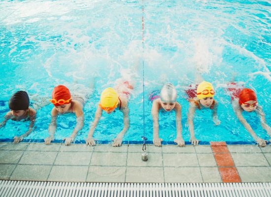 happy children kids group at swimming pool class learning to swim.