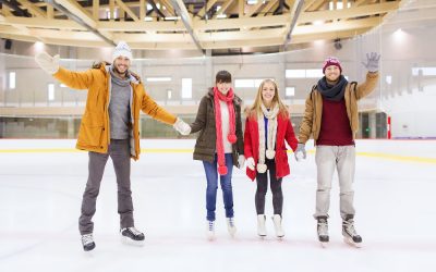 people, friendship, gesture, sport and leisure concept - happy friends waving hands on skating rink