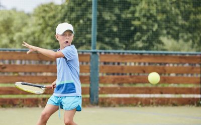 Talented little boy is learning playing tennis. Themes concentration, competition and skills.