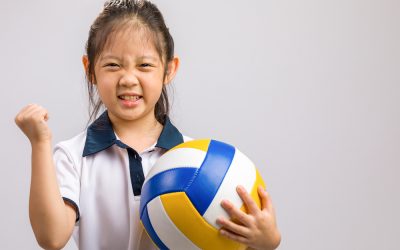 Child holding volleyball, studio shot, isolated on white.